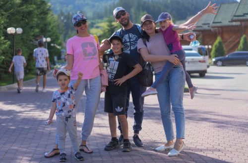 A joyful family of six spending quality time together in a scenic outdoor setting with mountains in the background.