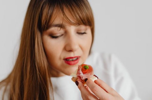 Woman with long hair savoring a gourmet canape indoors.